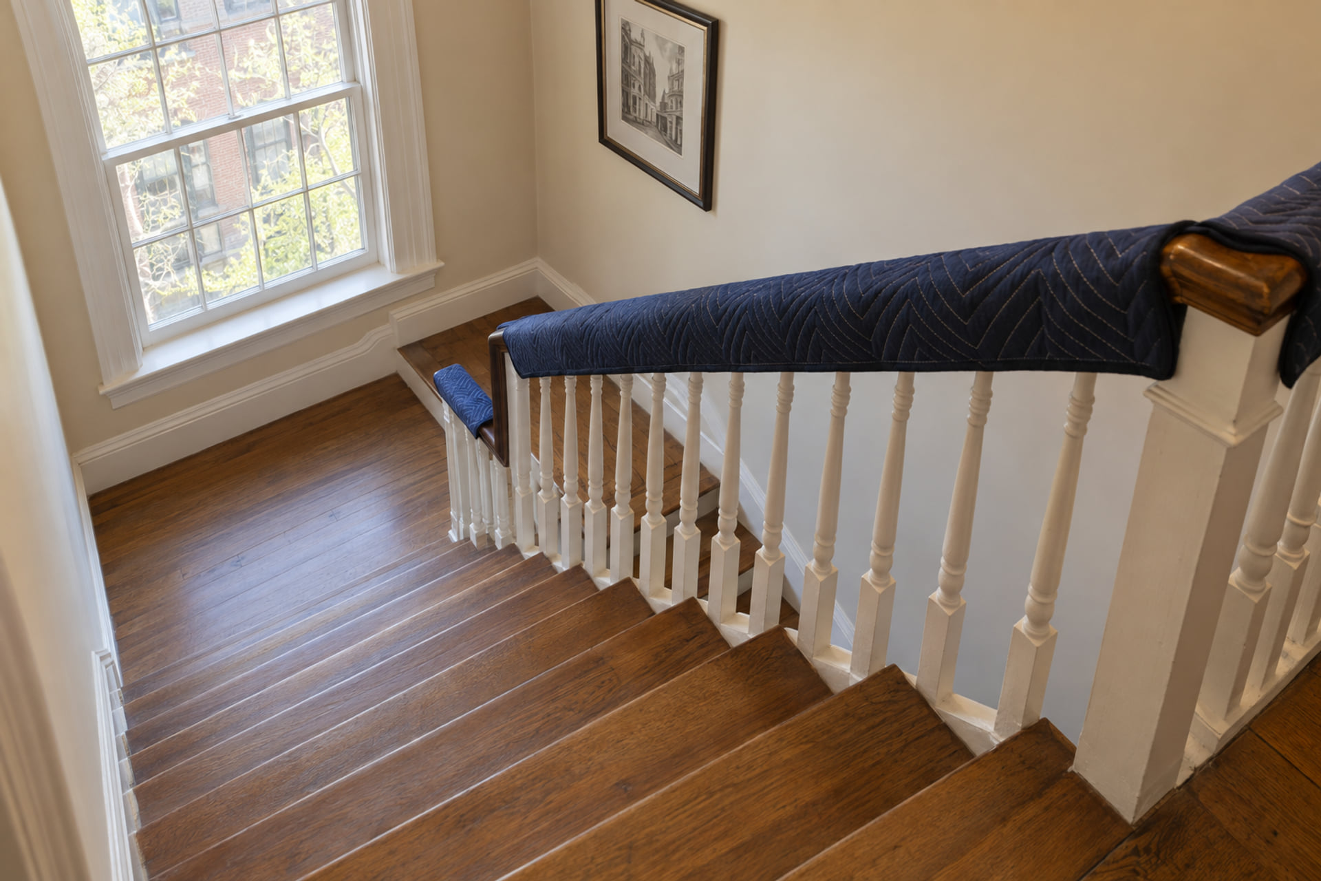 A narrow residential stair landing with a clear turn and protected handrail
