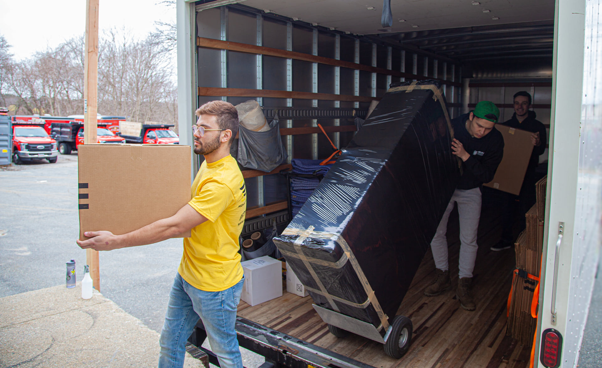 Milvus movers handling a carton and protected furniture at a truck
